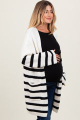 woman wearing a black and white striped maternity cardigan and holding her baby bump