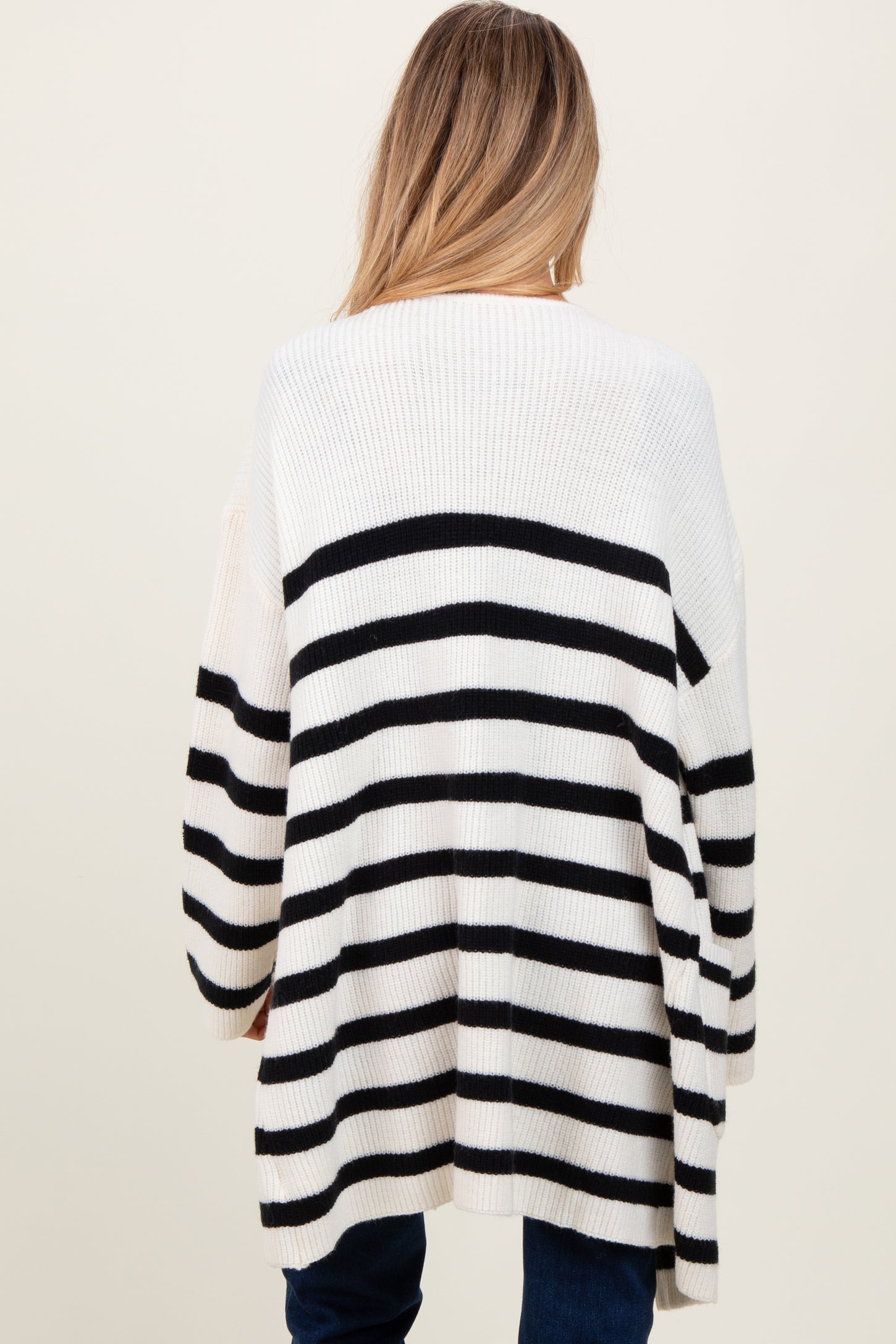 woman wearing a black and white striped oversized maternity sweater, view from the back
