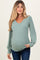 woman wearing a green ribbed maternity top with a v-neck and long sleeves, showing her baby bump