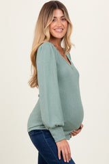 woman wearing a light green ribbed maternity top with puff sleeves and a visible baby bump