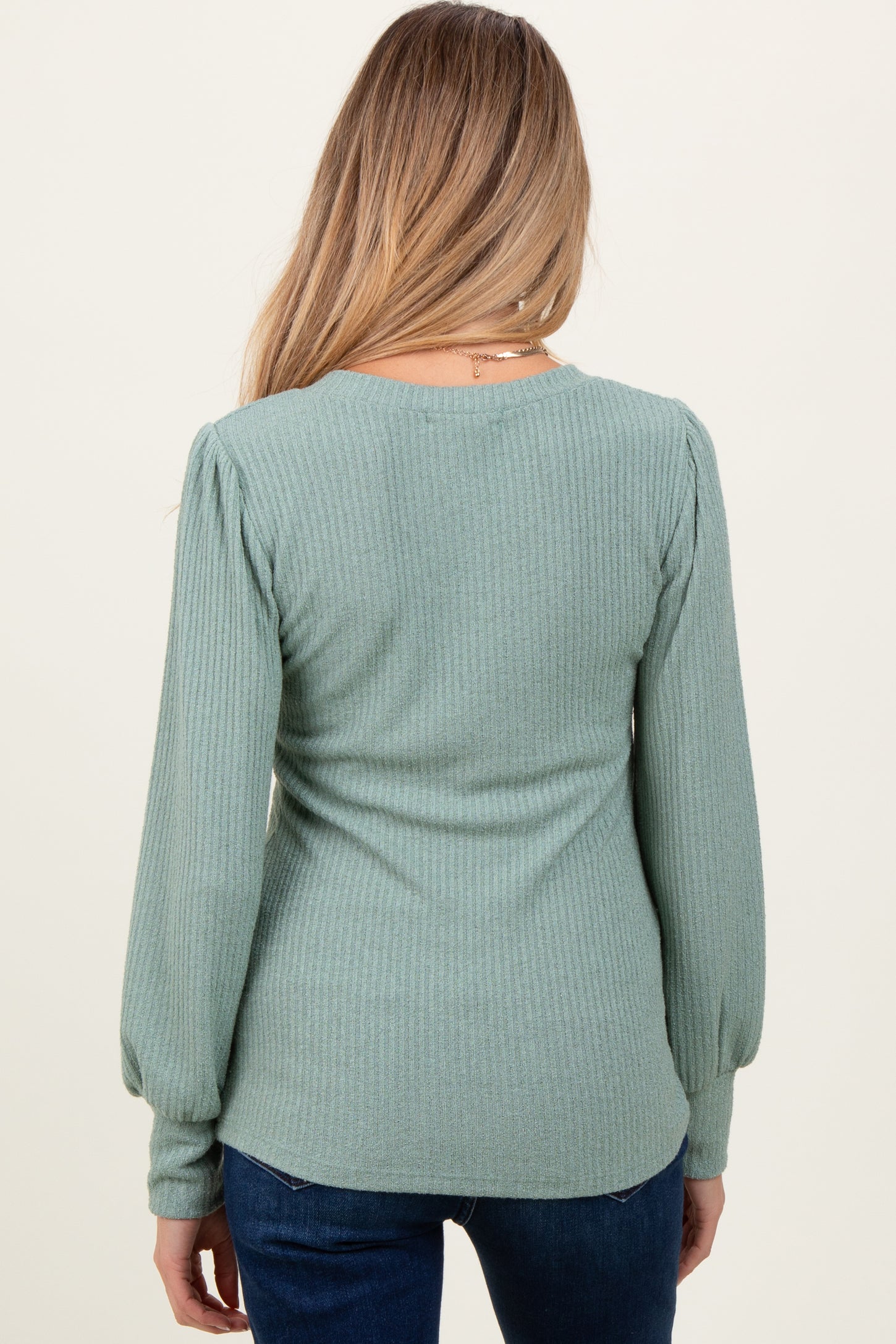 woman wearing a light green ribbed maternity top with puff sleeves, viewed from the back