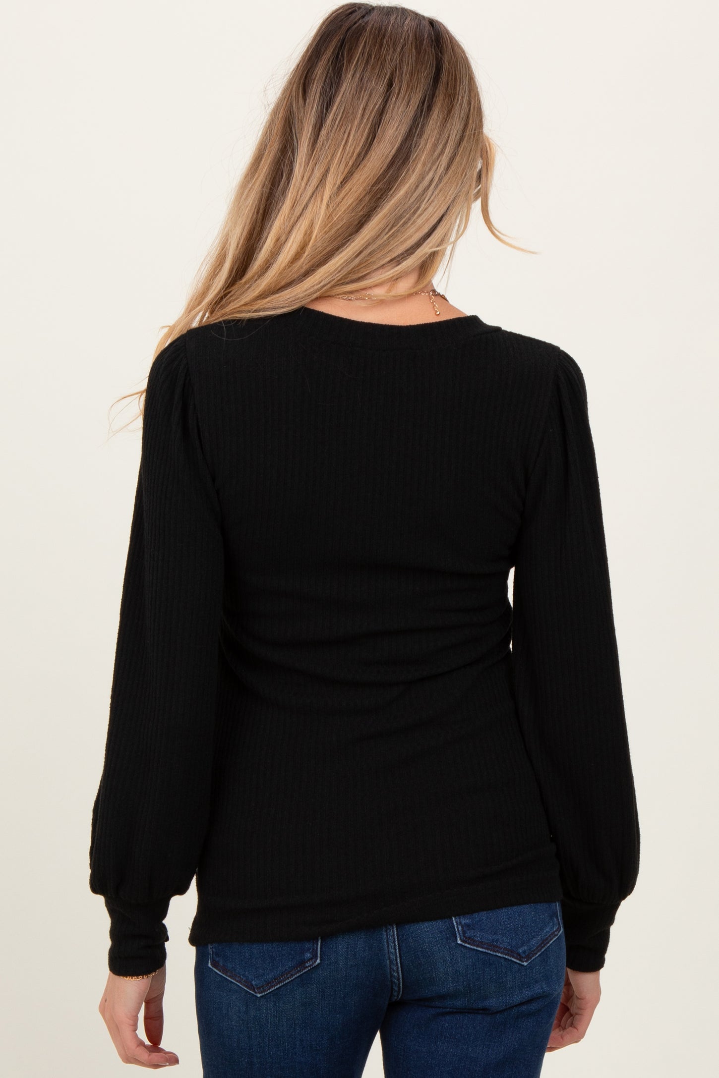 woman wearing a black long sleeve maternity top with puffed sleeves, viewed from the back