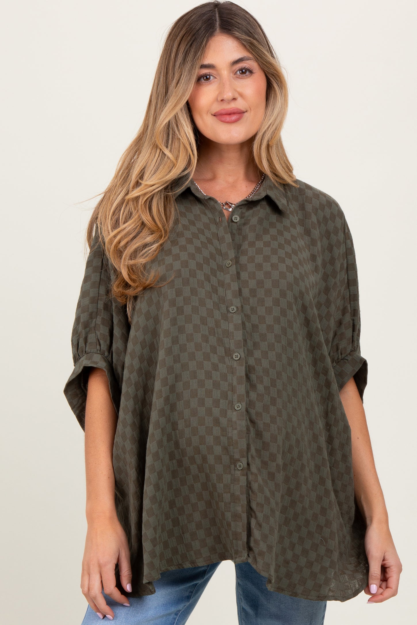 woman wearing a dark green checkered maternity shirt with rolled sleeves