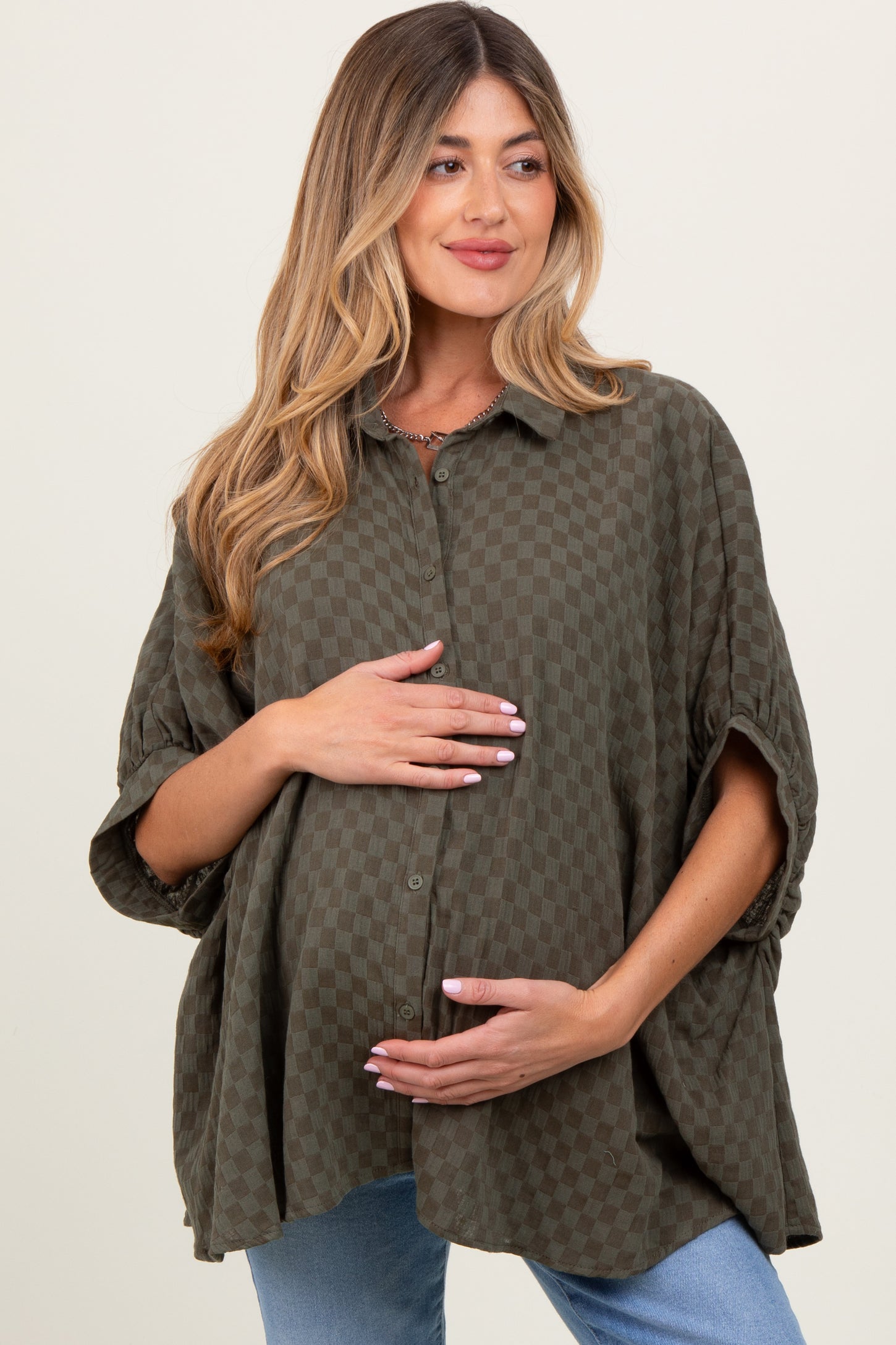 woman wearing a dark green checkered maternity shirt and holding her baby bump