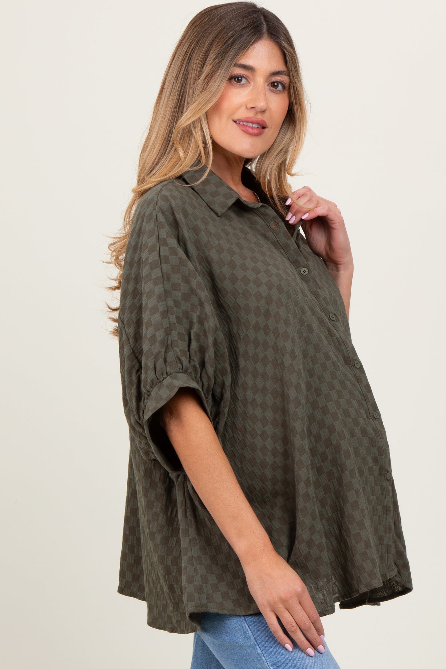 woman wearing a green checkered maternity shirt with a relaxed fit and rolled sleeves, showcasing her baby bump