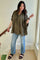 woman wearing a loose-fitting olive green checkered maternity shirt and light blue distressed jeans with black sandals
