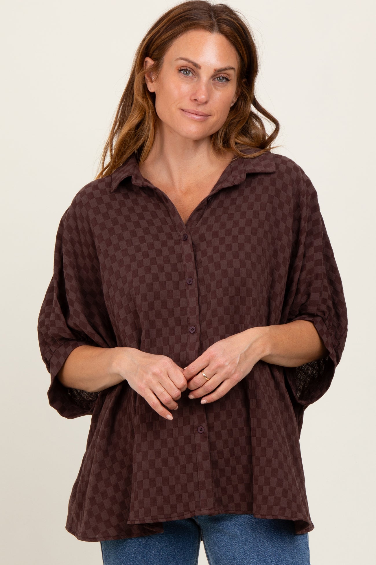 woman wearing a maroon checkered button-up shirt with a relaxed fit and rolled-up sleeves