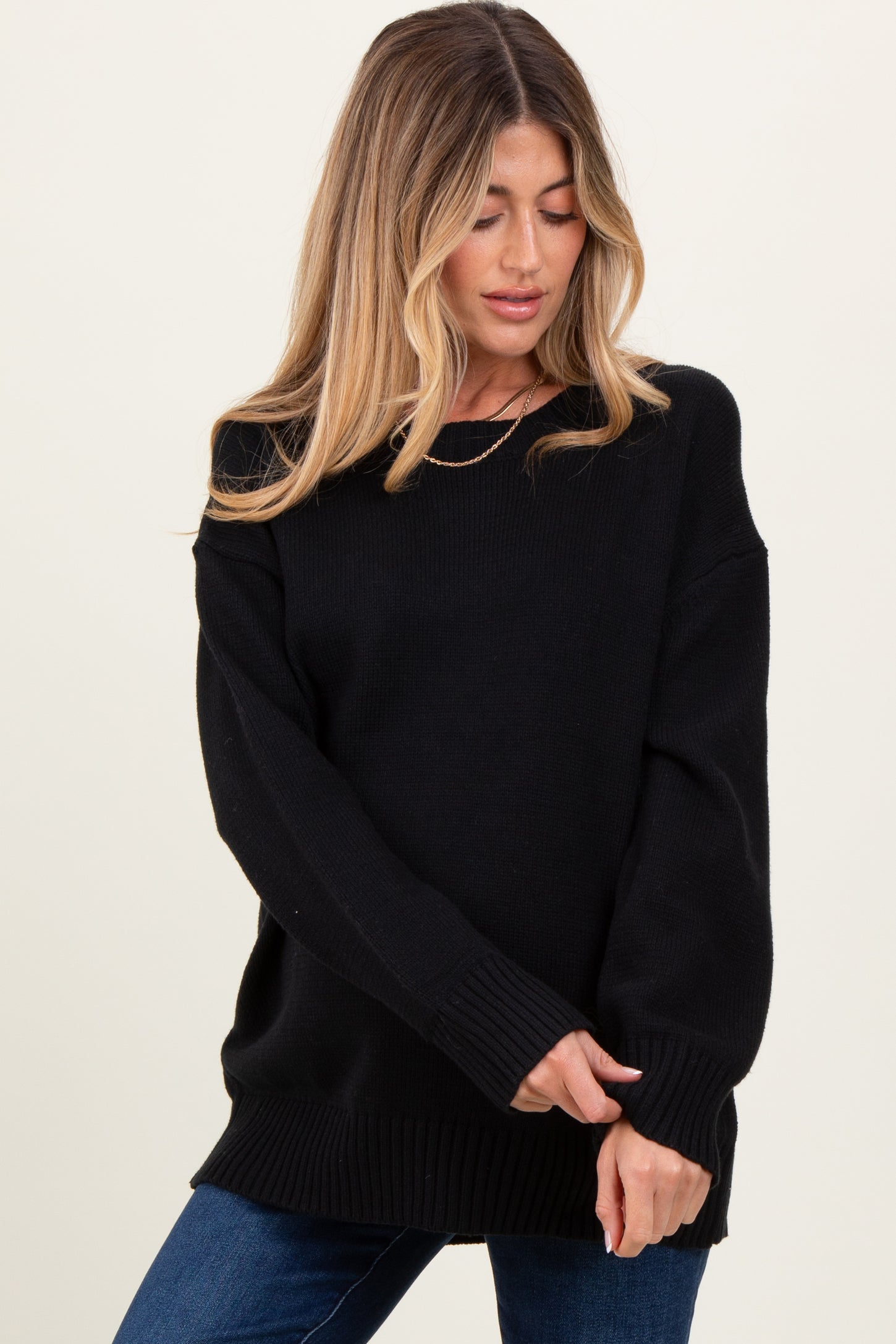 woman wearing a relaxed fit black maternity sweater with long sleeves and ribbed hem