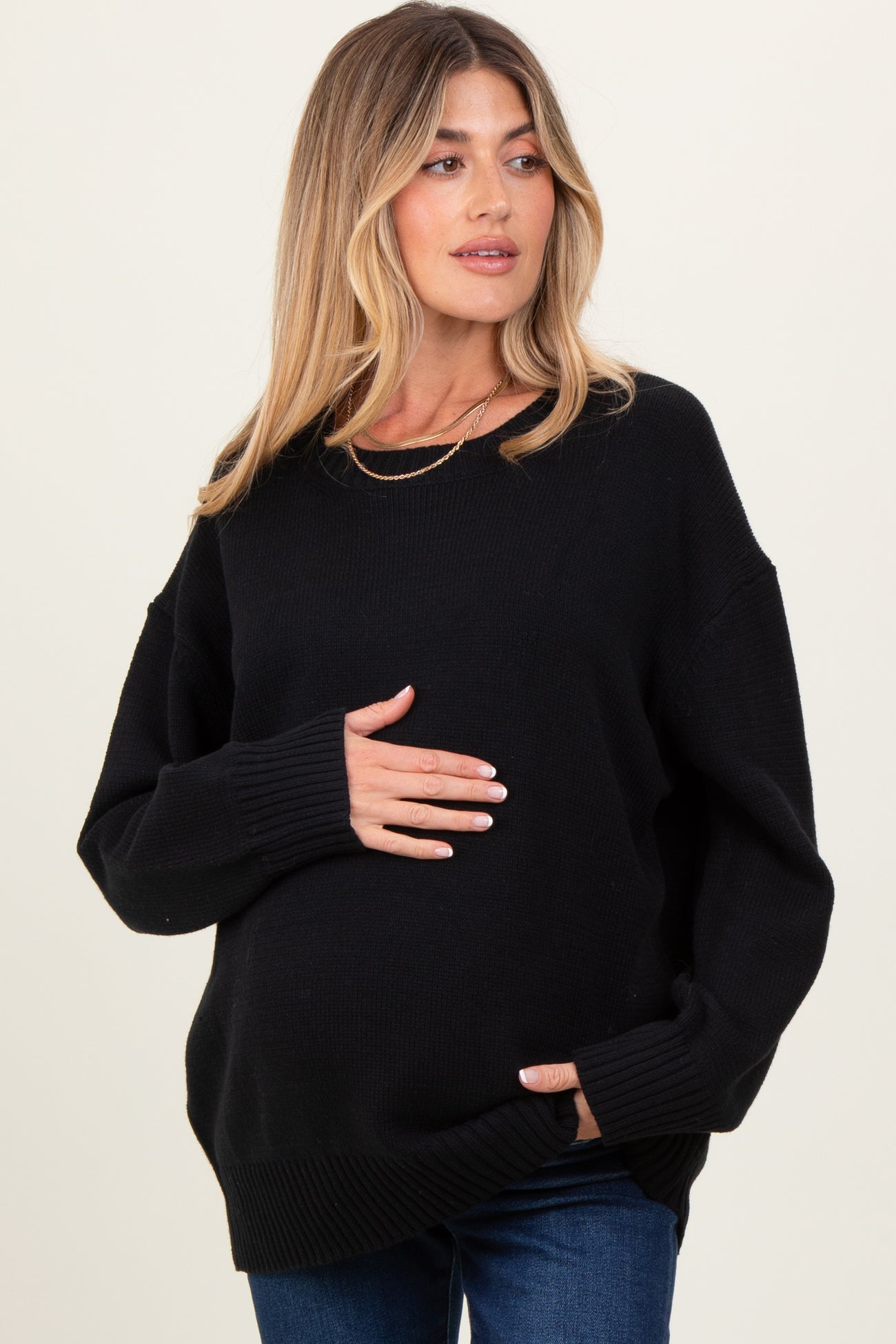 woman wearing a black oversized maternity sweater and holding her baby bump
