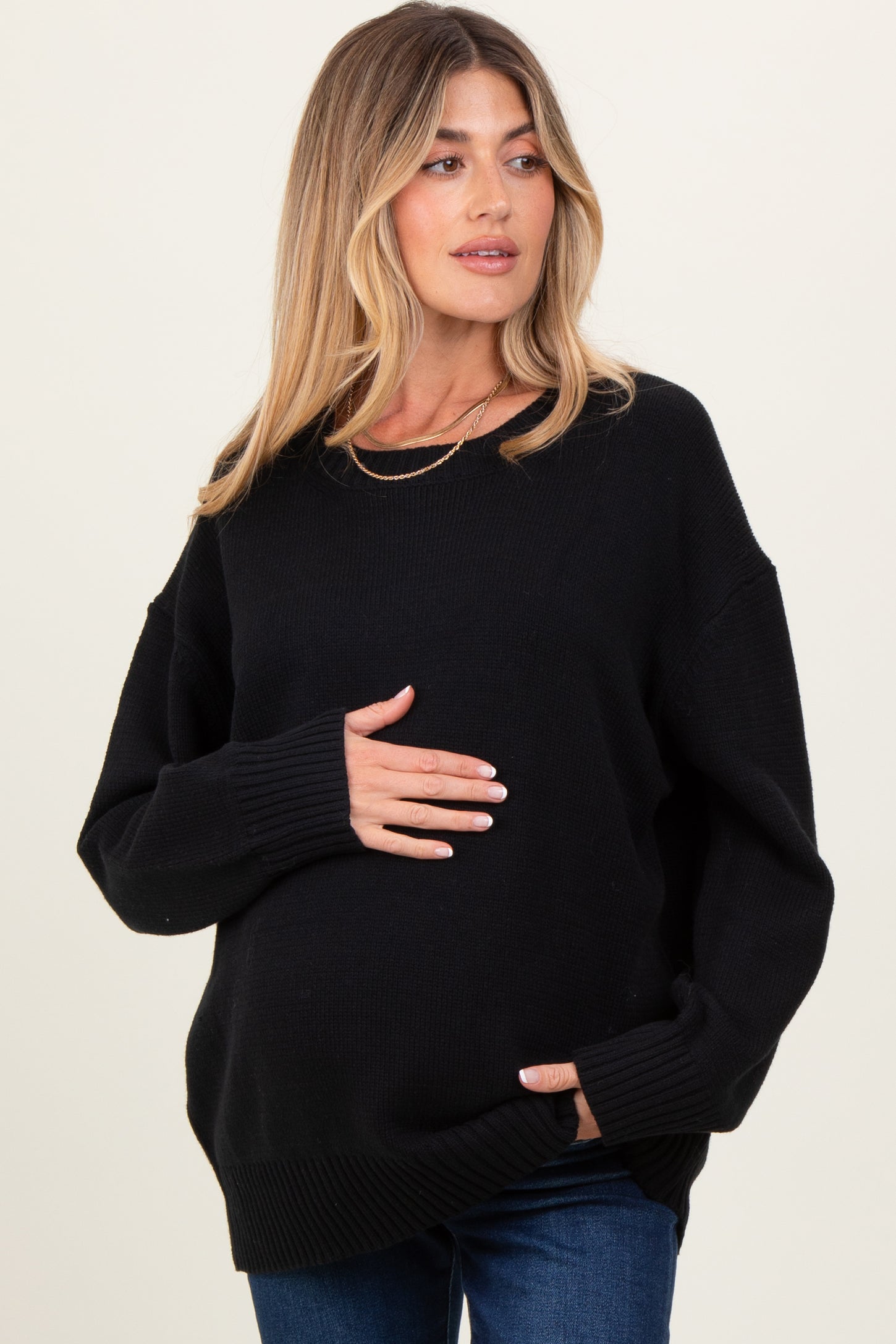 woman wearing a black oversized maternity sweater and holding her baby bump