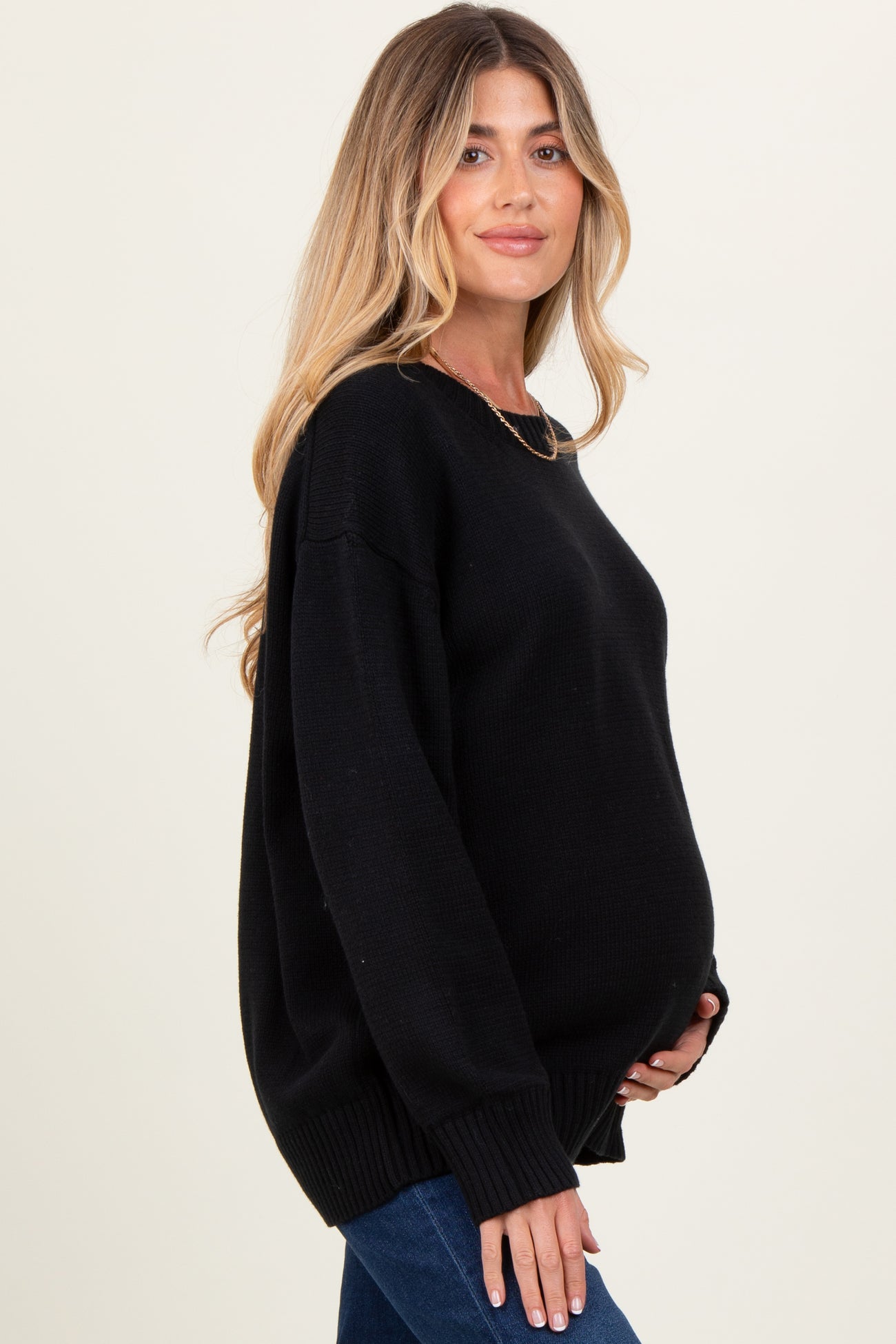 woman wearing a black oversized maternity sweater and holding her baby bump