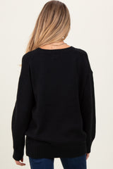 woman wearing a black oversized maternity sweater, seen from the back, showing relaxed fit and long sleeves