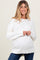 woman wearing a white oversized maternity sweater with long sleeves and a visible baby bump