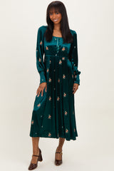 woman wearing a green velvet midi dress with floral embroidery and long sleeves