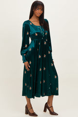 woman wearing a teal velvet floral midi dress with long sleeves and a tie neckline