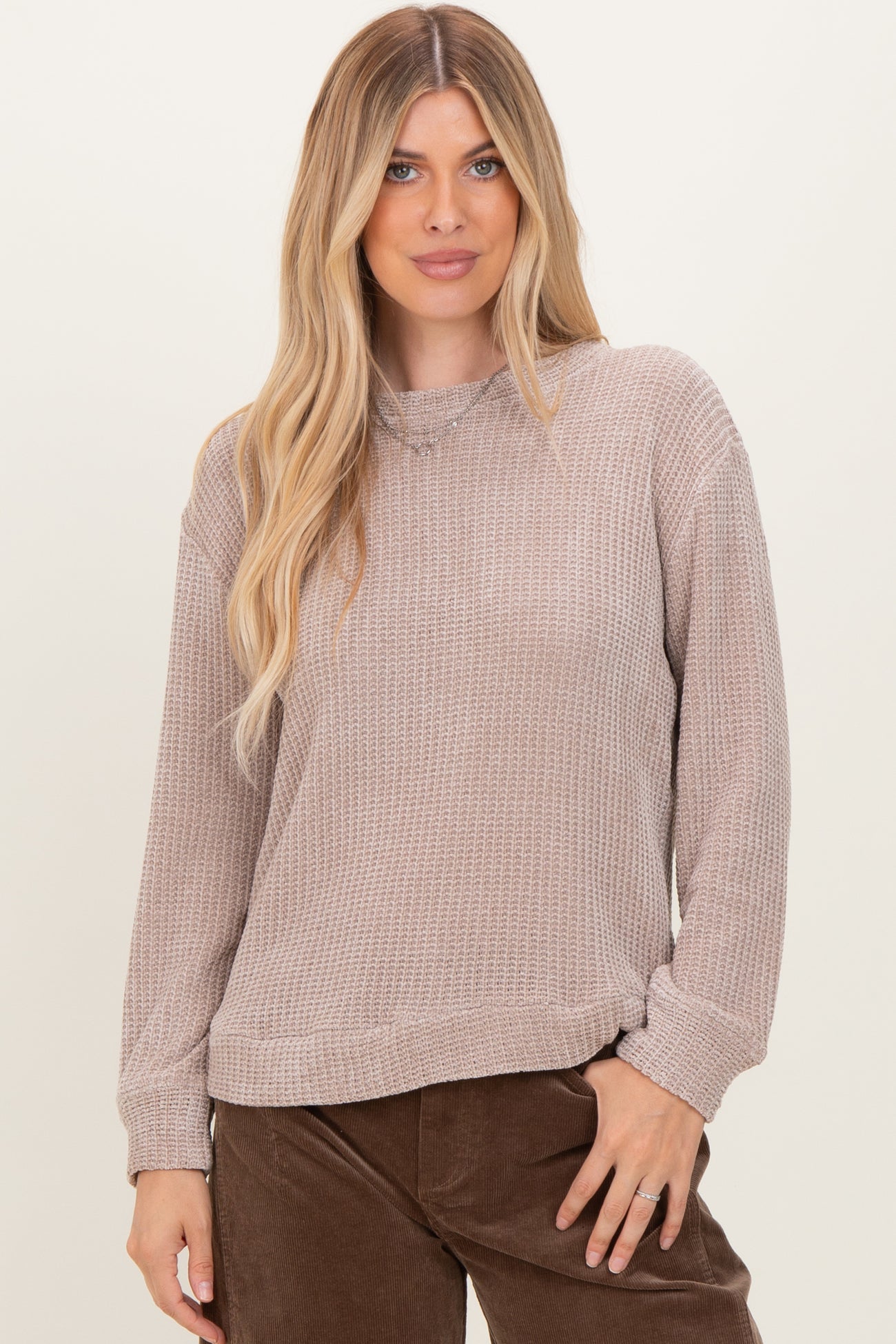 woman wearing a taupe long sleeve textured sweater with a relaxed fit and ribbed cuffs
