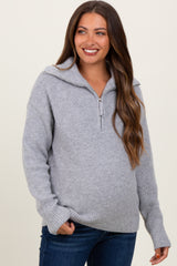 woman wearing a gray zip-up maternity sweater with a loose fit and a visible baby bump