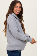 woman wearing a light gray maternity sweater with a high collar and a baby bump visible