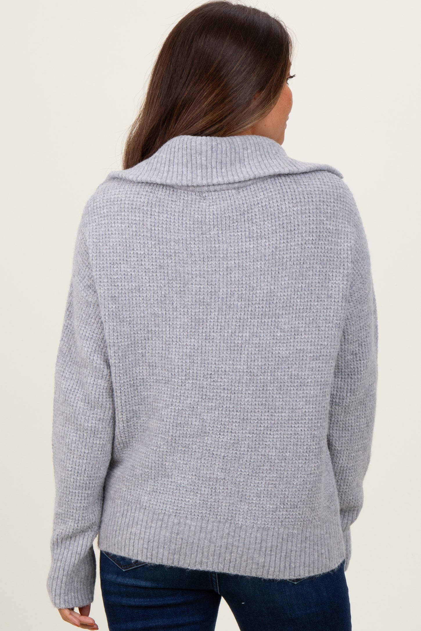 woman wearing a cozy gray maternity sweater with a fold-over collar, viewed from the back