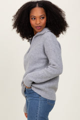 woman wearing a gray knitted pullover sweater with a collar and side pockets, paired with blue jeans
