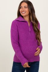 woman wearing a purple zip-up maternity sweater and holding her baby bump