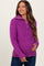 woman wearing a purple zip-up maternity sweater and holding her baby bump