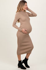 woman wearing a beige ribbed maternity dress, posing with her baby bump visible and styled with ankle boots