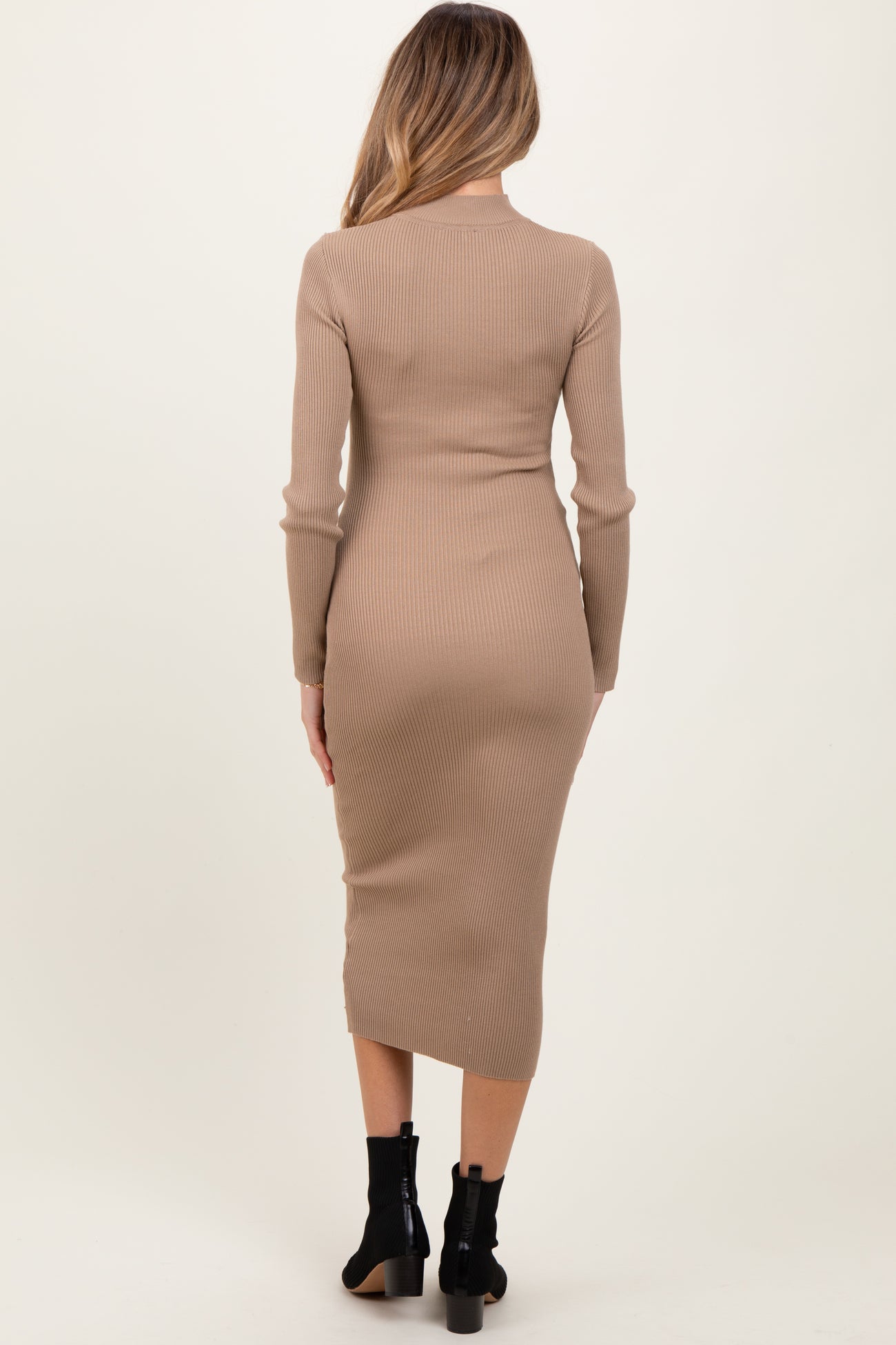 woman wearing a beige ribbed midi maternity dress, featuring long sleeves and a fitted silhouette