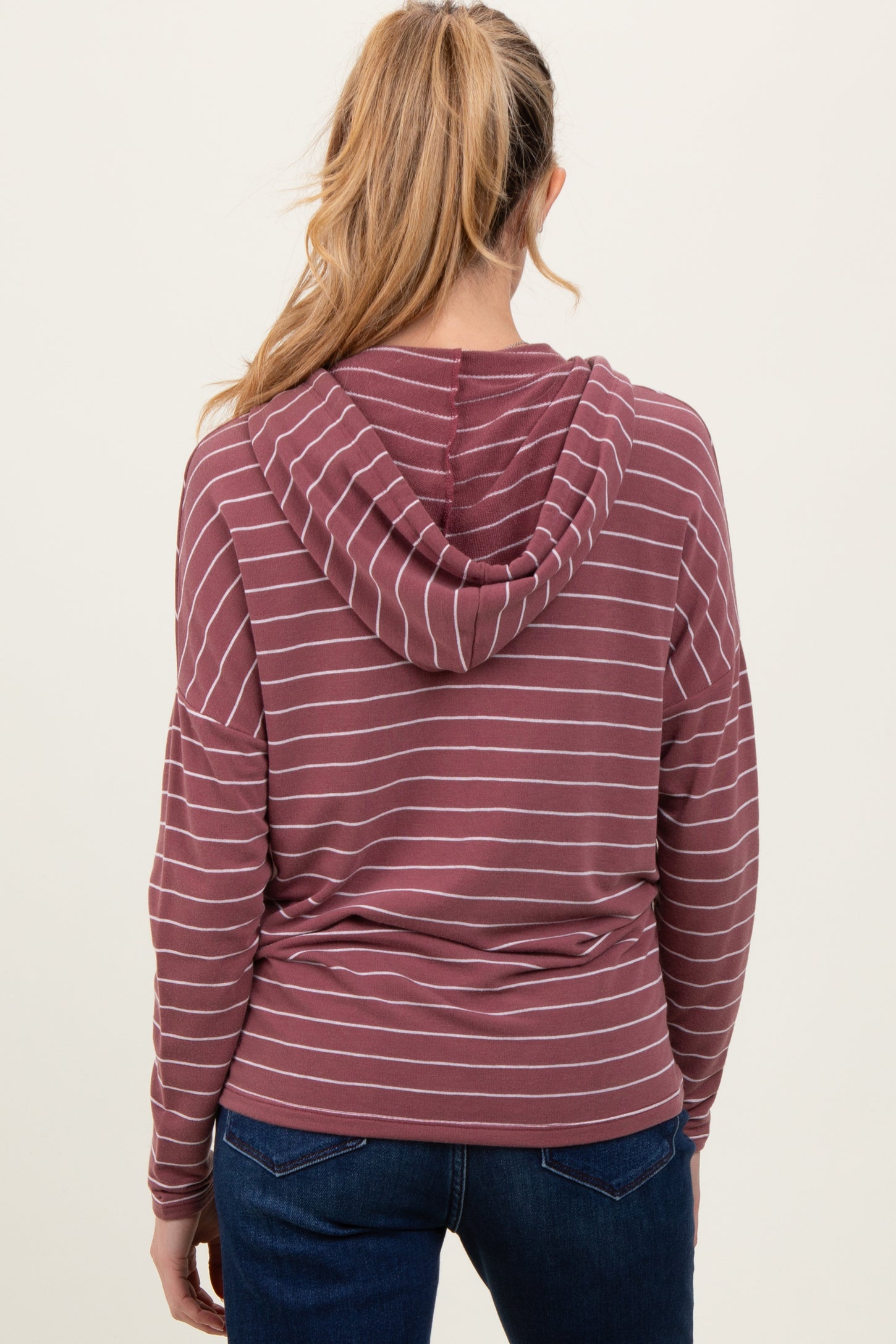 woman wearing a maroon and white striped maternity hoodie with a relaxed fit and a hood, viewed from the back