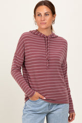 woman wearing a maroon and light gray striped hooded long sleeve sweatshirt with a relaxed fit and pockets
