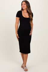 woman wearing a black ribbed maternity dress with short sleeves and a visible baby bump