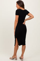 woman wearing a black short sleeve ribbed maternity dress with a side slit, showing her back and playful pose