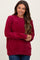 woman wearing a burgundy chunky knit maternity sweater with long sleeves and a relaxed fit