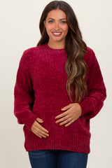 woman wearing a burgundy oversized knit maternity sweater and holding her baby bump