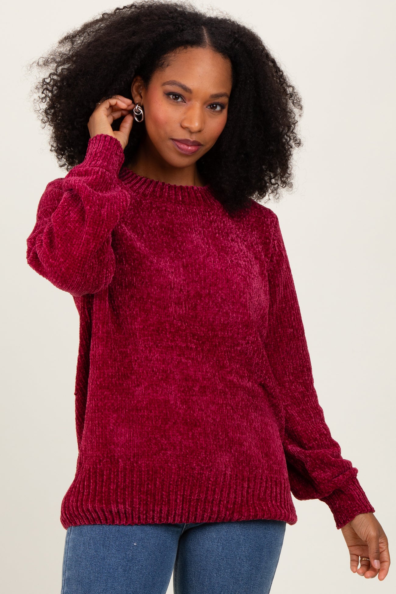 woman wearing a maroon plush sweater with a relaxed fit and ribbed hem, styled with loose jeans
