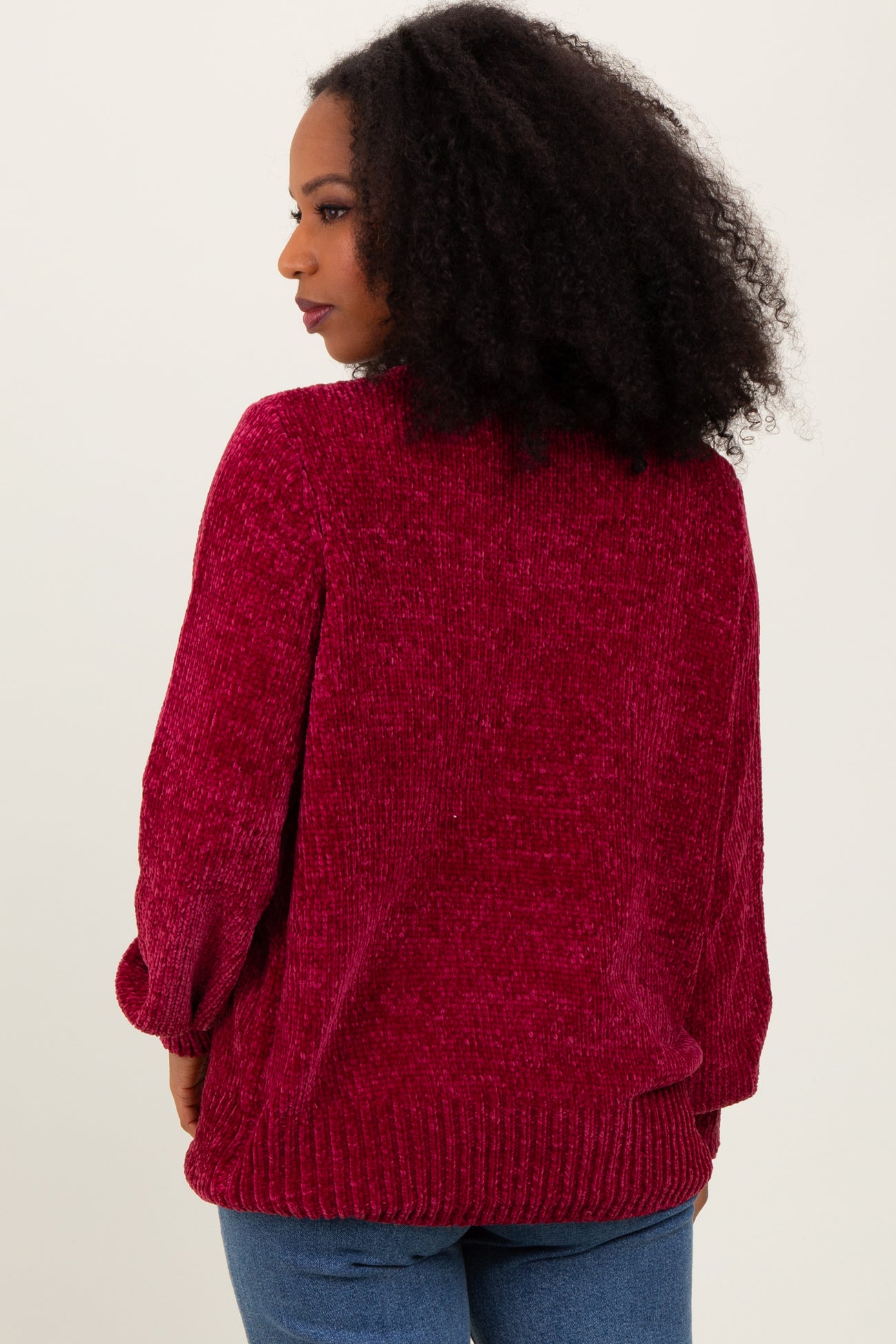 woman wearing a burgundy chunky knit sweater with balloon sleeves and a relaxed fit, seen from the back