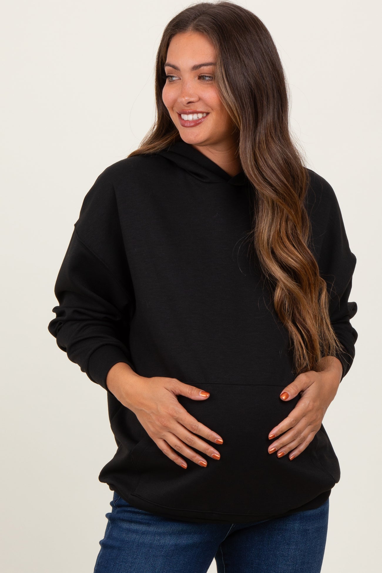 woman wearing a black maternity hoodie and holding her baby bump