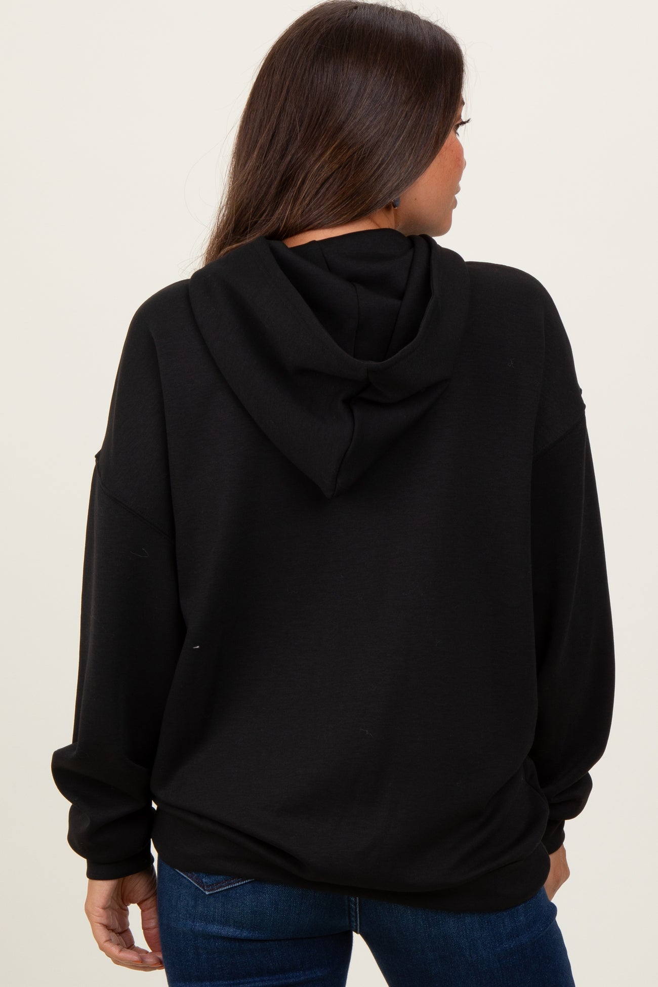 woman wearing a black maternity hoodie, seen from the back, with a relaxed fit and an attached hood