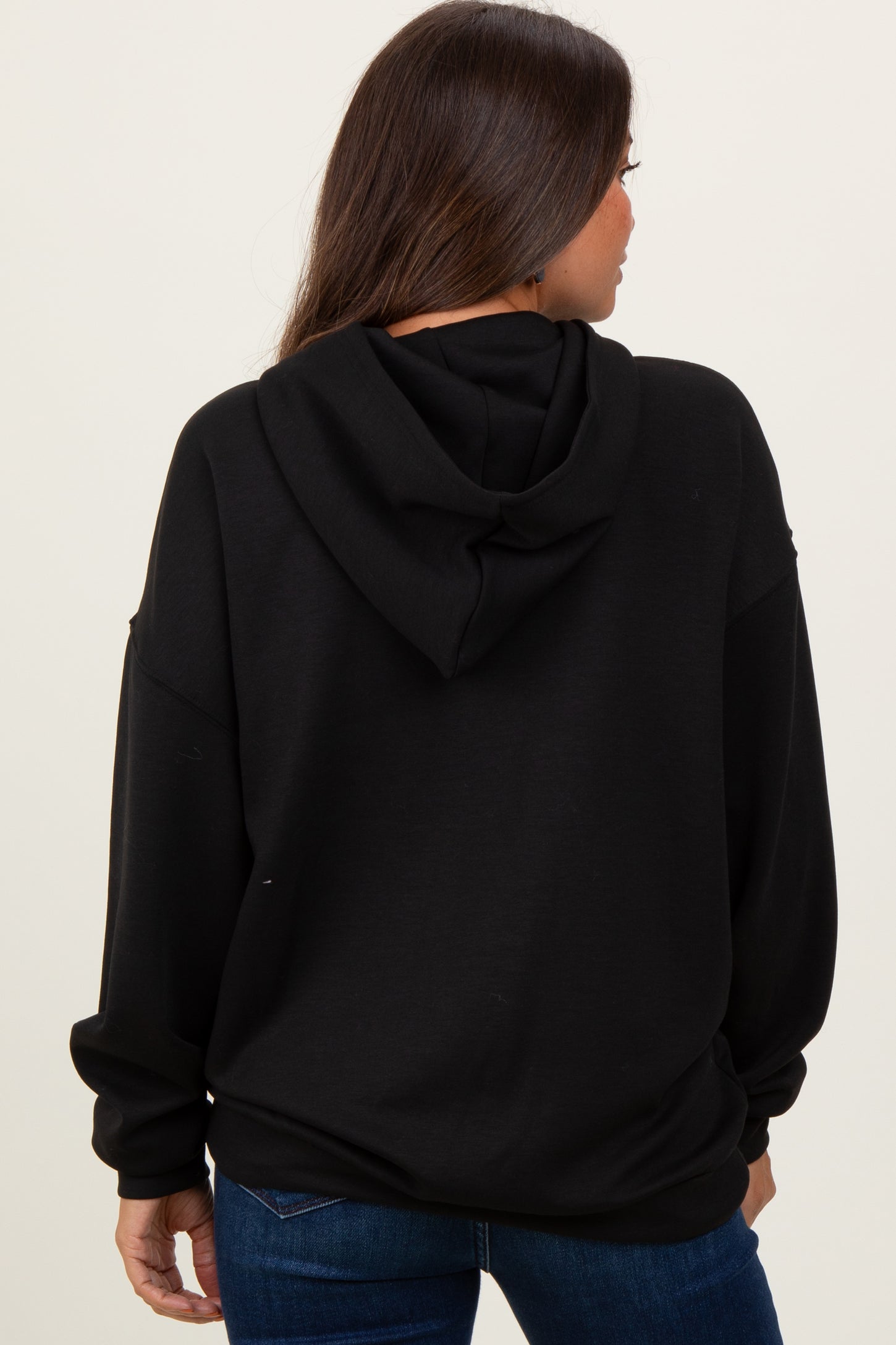 woman wearing a black maternity hoodie, seen from the back, with a relaxed fit and an attached hood