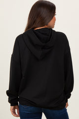 woman wearing a black maternity hoodie, seen from the back, with a relaxed fit and an attached hood