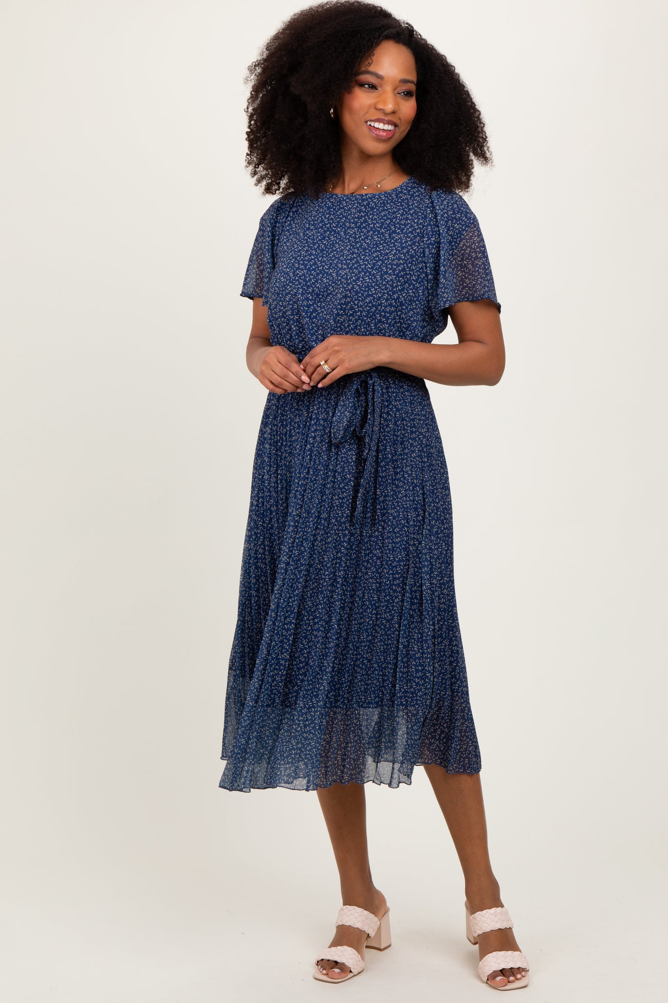 woman wearing a navy blue floral midi dress with short sleeves and a tie waist detail