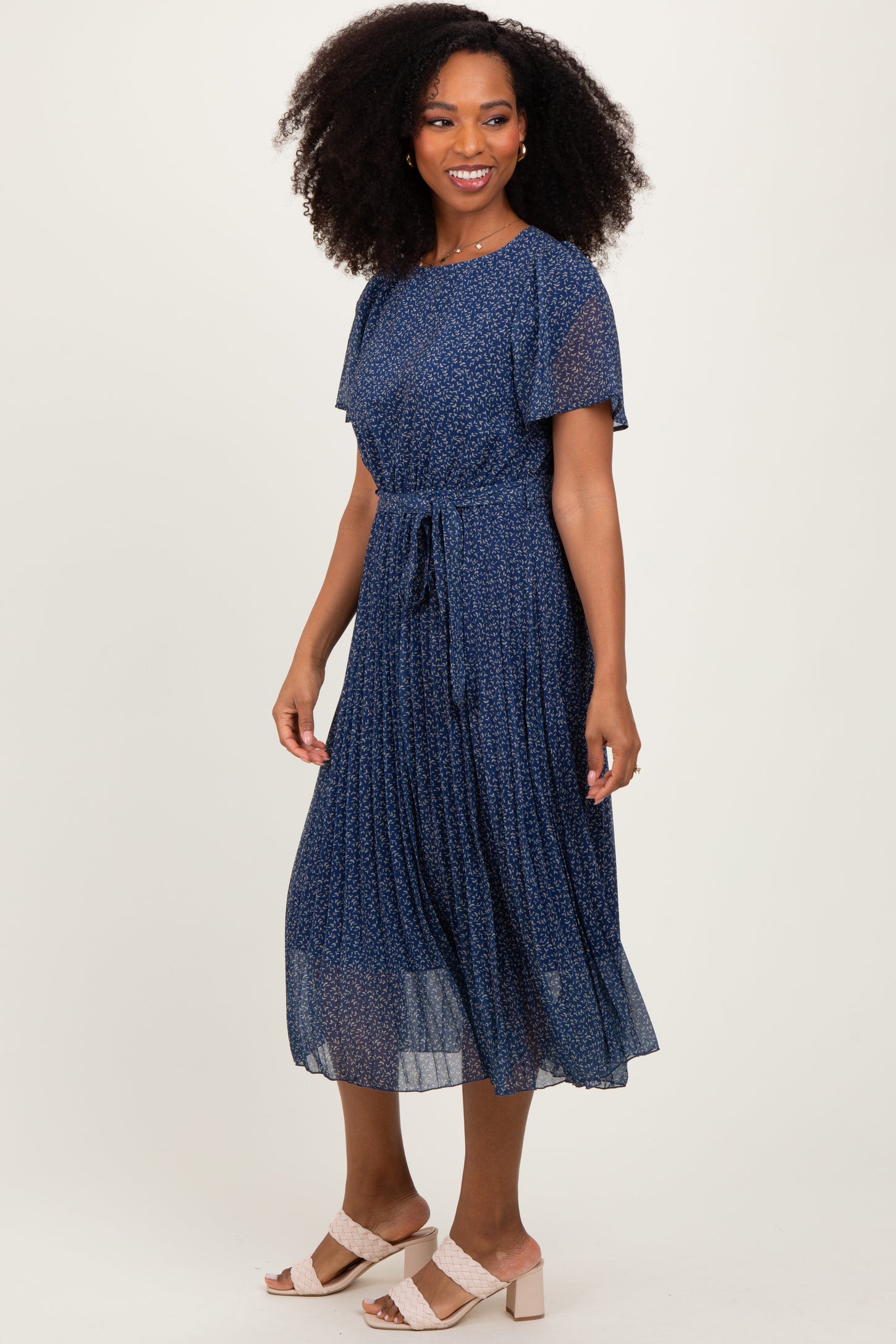 woman wearing a navy blue floral midi dress with short sleeves and a tie waist detail