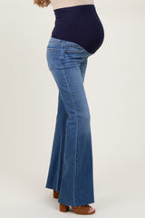 woman wearing a pair of light blue maternity flare jeans with a navy belly panel, highlighting a visible baby bump