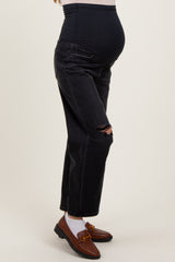 woman wearing black ripped maternity jeans with a supportive belly panel and brown loafers, showing her baby bump