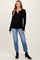 woman wearing a black ribbed maternity top with button details and blue jeans, showcasing a visible baby bump