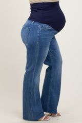 woman wearing a navy blue maternity tank top and blue flared maternity jeans, showing her baby bump