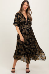 woman wearing a black floral print maternity dress with a v-neck and short sleeves, smiling at the camera