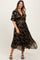 woman wearing a black floral print maternity dress with a v-neck and short sleeves, smiling at the camera