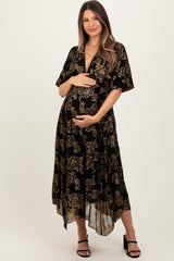 woman wearing a black floral maternity dress with a flowy hem and a baby bump, standing and holding her belly