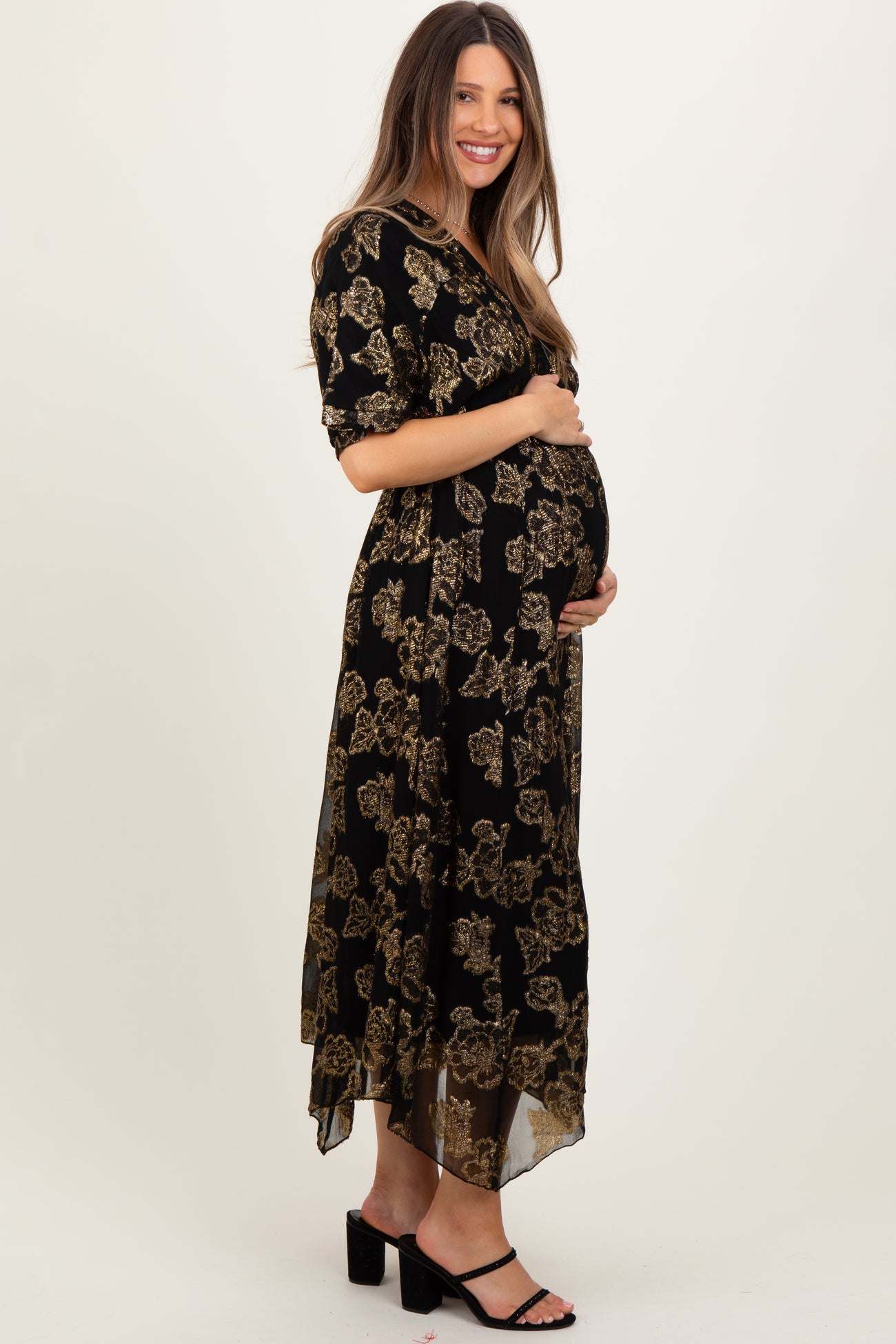 woman wearing a black floral print maternity maxi dress and showcasing her baby bump